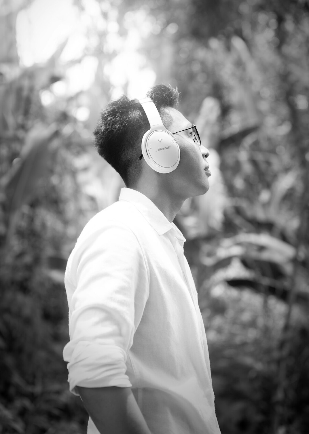 Young Malaysian man wearing glasses with headphones around his neck, smiling